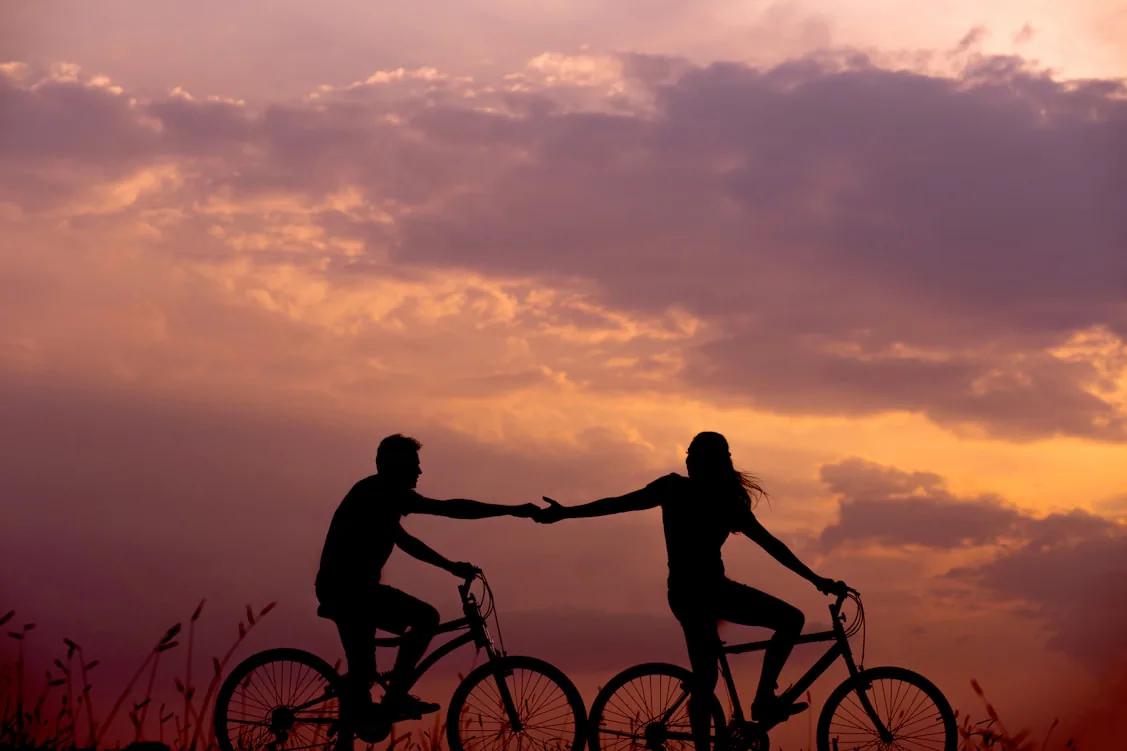 Two people reaching toward each other while cycling